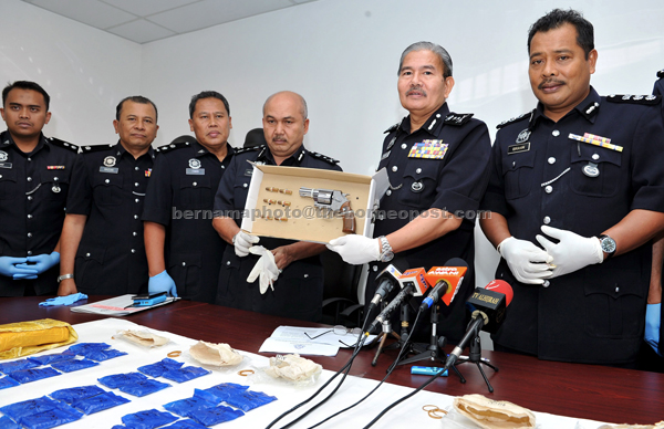 Mazlan (second right) shows the seized drug and  firearm during a press conference at the Customs, Immigration and Quarantine Complex. — Bernama photo