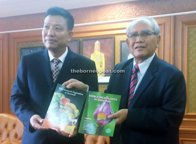 Jabu (right) presenting books about Sarawak to Liu as souvenirs during the courtesy call.