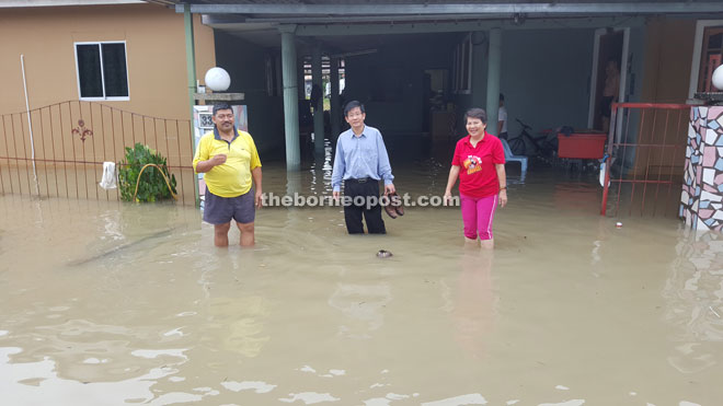 Tan (centre) visits one of the houses affected by the flash floods in Kuching.