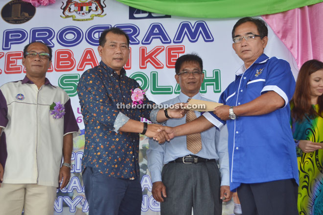 Ugak (second left) presents an MRP cheque to Tuai Rumah Edison Lugad of Jalan Melekun. 