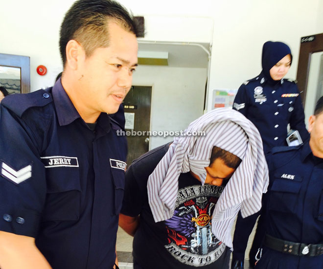 Ramzan (middle) being led away from the courtroom yesterday after he was charged with murdering his friend at the  Kota Kinabalu International Airport.