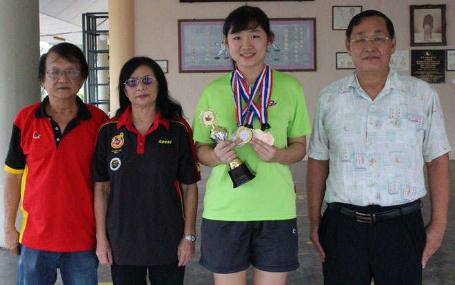 Alice displays the medals and trophy that she won in recent competitions alongside (from left) coach Chua Chiaw Lian, KDTTA chairman Christina Helena Wee and her father Clement Chang.