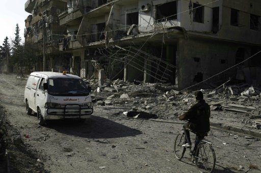  AFP | An ambulance drives past heavily damaged buildings following reported air strikes in a rebel-held area on the outskirts of the capital Damascus, on February 12, 2016 