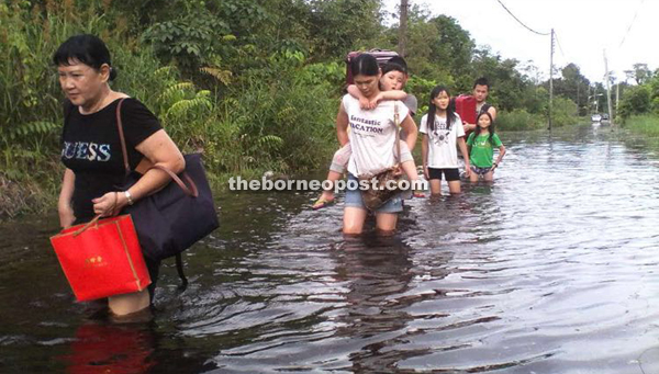 Residents wading through the flooded road to go home.