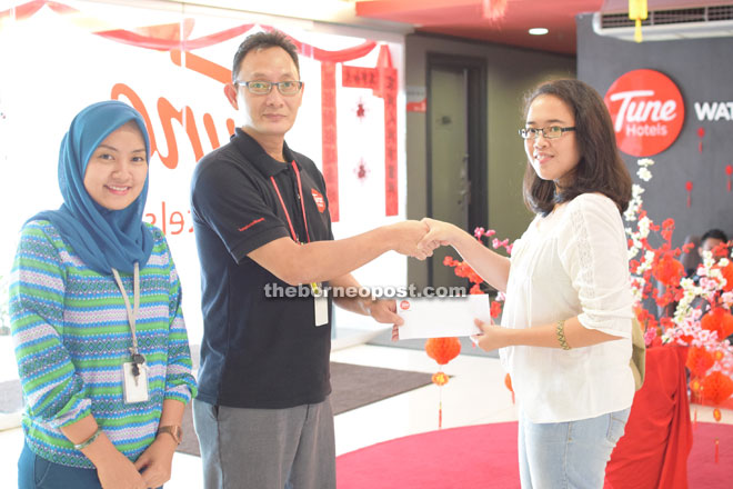 Tune Hotel manager Gary Johnny (second left) hands over the lucky draw vouchers to Borneo Post SEEDS writer Danielle Sendou Ringgit as sales marketing executive Nor Fauzana Wahid looks on.