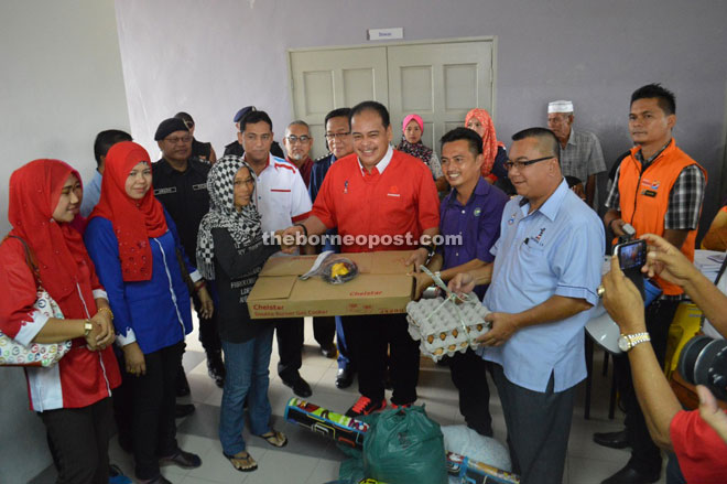 Samsudin (middle) presenting contribution to one of the fire victims.