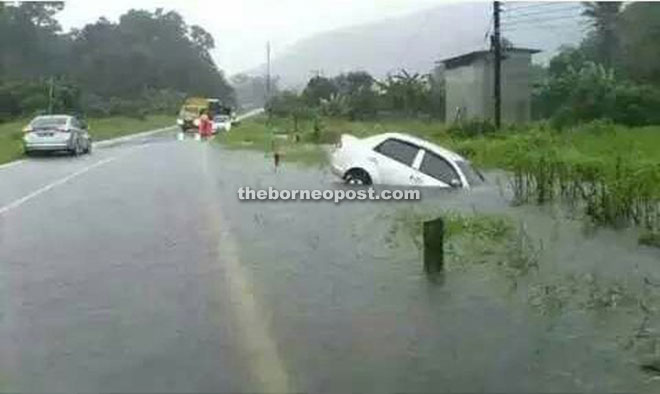 A car is seen in a ditch along road leading to Kampung Pandan in Lundu.