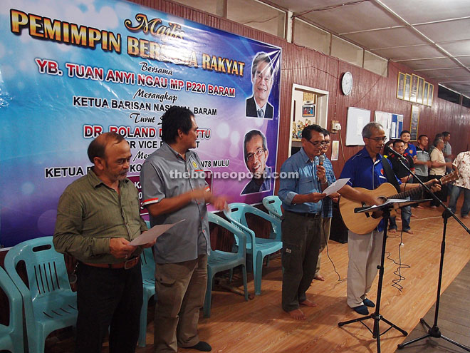 Dr Roland (right) entertains the audience with his guitar and song he composed called ‘This Is Our Land’ while Anyi (second left) and others listen.