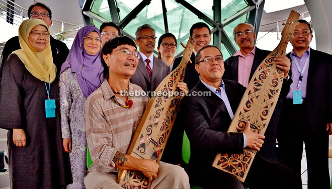 Abdul Hakim (seated right) fiddles with the sape that was handed to him by Mathew (seated left). 