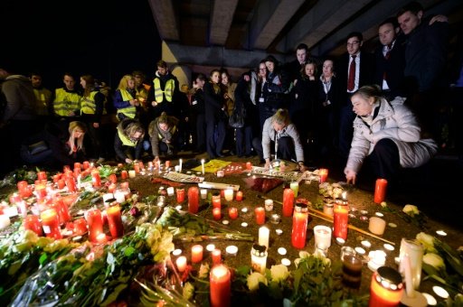Belga/AFP / by Pauline Froissart | Brussels airport workers and their relatives pay tribute to the victims of Brussels triple attacks at a makeshift memorial near the airport in Zaventem on March 23, 2016 