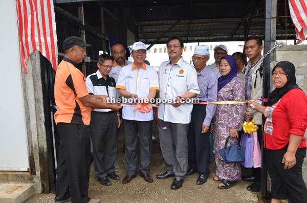 Madius cuts the ribbon to mark his visit to the compost centre. On his left Dr Hazland.