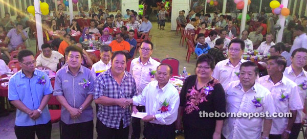 Nansian (right) handing over an MRP fund to a recipient at the meet-the-people session held at Balai Raya Tondong, Bau on Friday night in the presence of Lee (2nd left) and others.