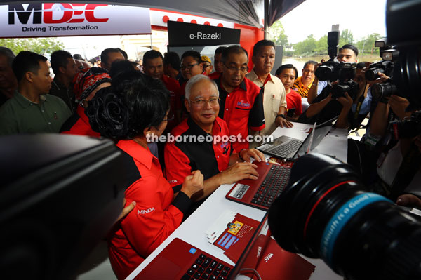 Najib (seated) visits a booth after launching Minda. 
