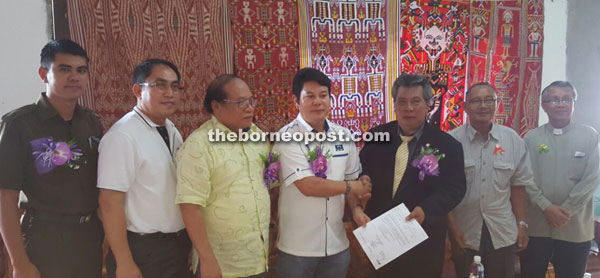 Rayong (centre) handing over a letter of appointment to community leader Betok at Simpang Jengin on Friday. Also seen is Nyalau (third left).
