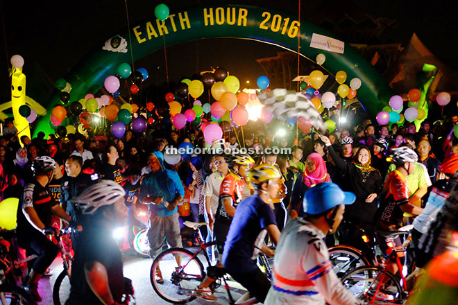 GOING GREEN : Samariang assemblywoman Sharifah Hasidah Sayeed Aman Ghazali (background, right) flags off the cyclists and participants of the Earth Hour Colourful Ride at the Kuching Waterfront. — Photo by Russell Ting
