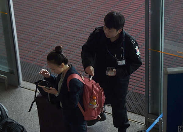A security guard swipes a woman to check for explosives, at an entrance to the airport in Beijing. — AFP photo