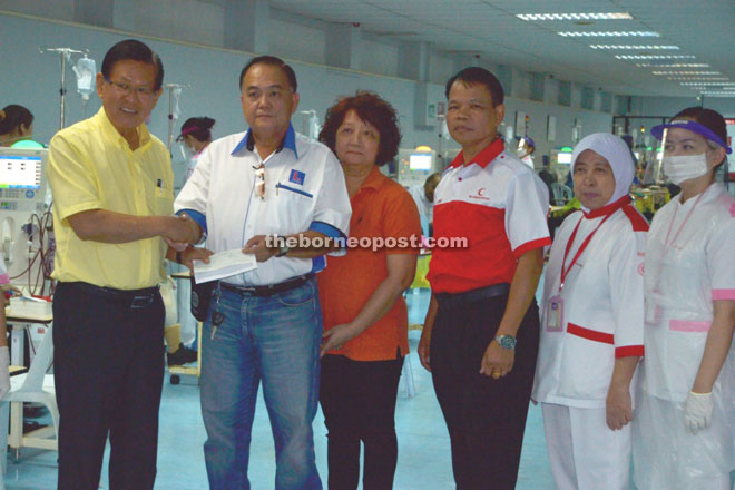 Lee (left) receives the RM50,000 donation from Bong, who is the relative of the anonymous donor. 