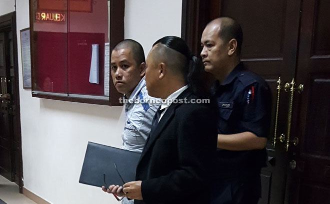 Asri being escorted by a policeman at the court room.