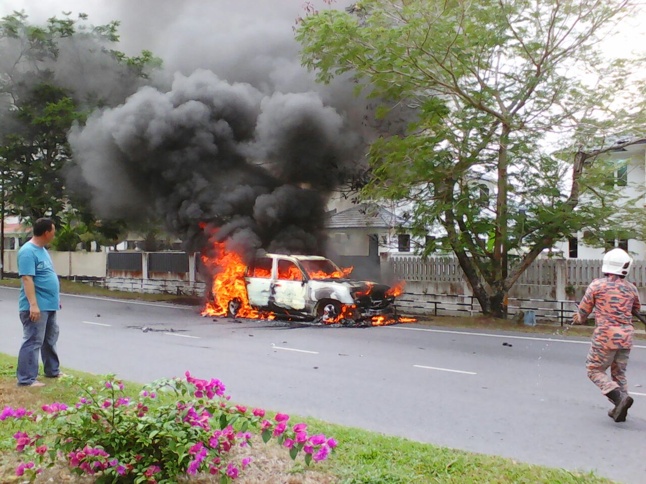 The car is seen ablaze at the roadside.