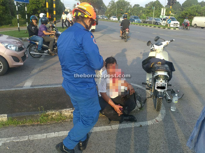 A Civil Defence Department  member attending to the injured motorcyclist in the accident near Sungai Apong.