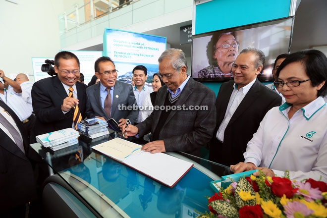 Adenan (centre) visiting the Petronas booth, accompanied by (from left) Abdullah and Len. — Photo by Kong Jun Liung