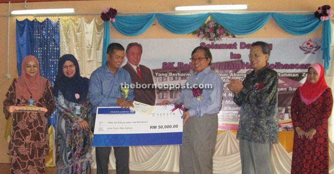 SK Rakyat PTA chairman Mohd Asman Ahmad (third left) receiving a mock cheque from Abang Johari yesterday. —Photo by Jeffery Mostapha. 