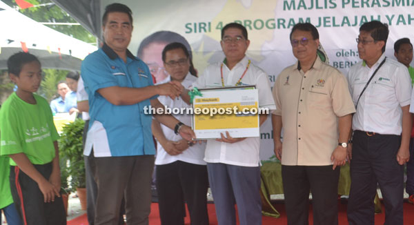 Dr Maximus (third right), flanked by Deputy Rural and Regional Development Minister Datuk Alexander Nanta Linggi (second right) and Deputy Kapit Resident Minggu Jampong, hands over the RM1,000 activity fund to SK Kampung Baru headmaster Sham Sepah.