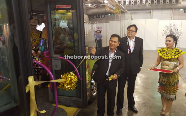 Ik Pahon (left) preparing to cut the ribbon and launch the SBS transit bus wrap advertising campaign. Also seen is Lim (centre).