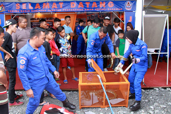 Visitors take a closer look as officers from the Civil Defence Department demonstrate the snake-handling skill. 