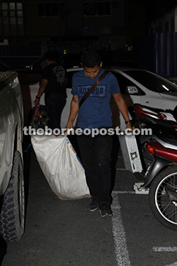 A CID personnel carrying the seized items to the  police station. 