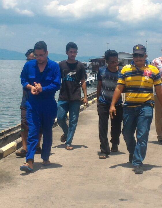 The ship's (in blue) is brought to the Tawau police station for questioning. 