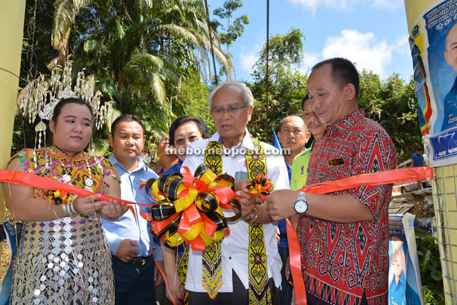 Jabu cutting a ribbon to officially declare open the new bridge at Rumah Cosmas.