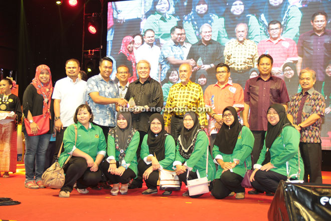 Awang Tengah (fifth left) presents an award to Sufian Mohat the chairman of Limbang District Council for being adjudged the best booth. 