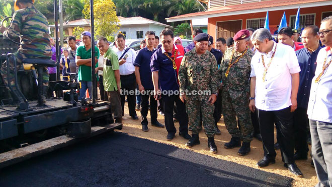 (From right) Ismail, Ahmad Zahid and Zulkifeli take a closer look at a tar-sealing of road demonstration by army personnel.