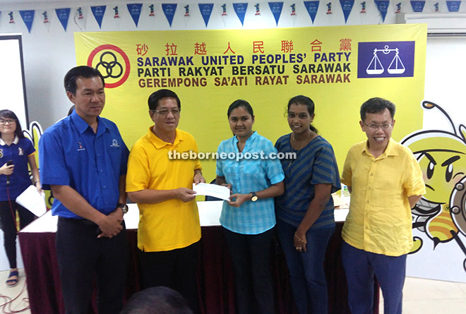 Tan (second left) presenting the cheque to representatives from Kuching Hindu Youth Organisation. Dr Sim is at right while at left is Tan.