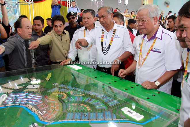 Adenan (centre) discusses the project with Morshidi (on his right) and Manyin (on his left) as they look at the development model. — Photo by Chimon Upon