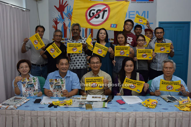 See (seated, second left) and Tan (seated, left) showing the anti-GST brochure while Baru (seated, centre), Voon and other party members showing the ‘Rakyat Bangkit Bantah GST’ flags.