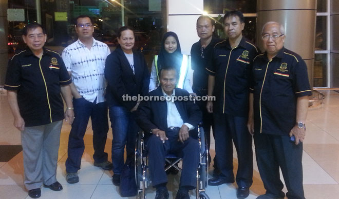 Awang on a wheel chair poses with PVTKR members at Kuching International Airport. 