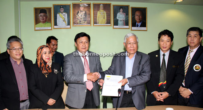 Manyin (third right) receives documents from Mawan following the handing-over of duties. Also seen are senior officers from the ministry, including Rosey (second left). — Photo be Chimon Upon