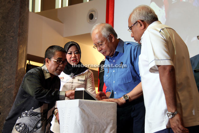 Najib (second right) activates the tablet as a gimmick to launch the ceremony to present the gadgets to school teachers.