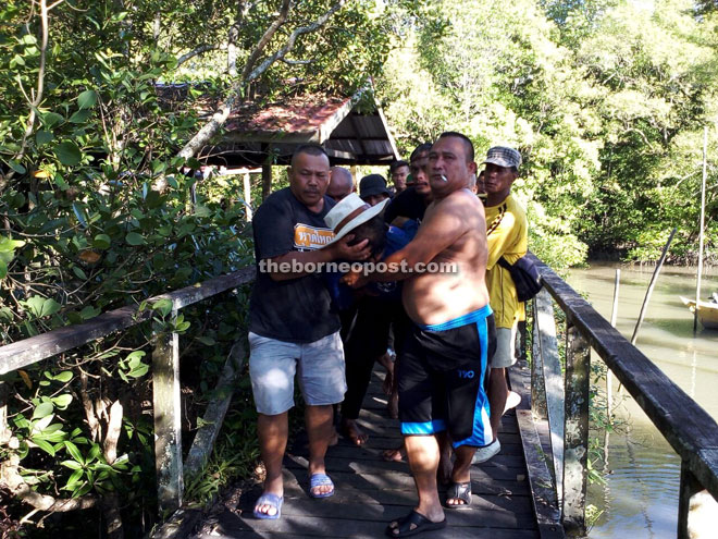 Fishermen carry the victim on arrival at Kampung Buntal jetty.