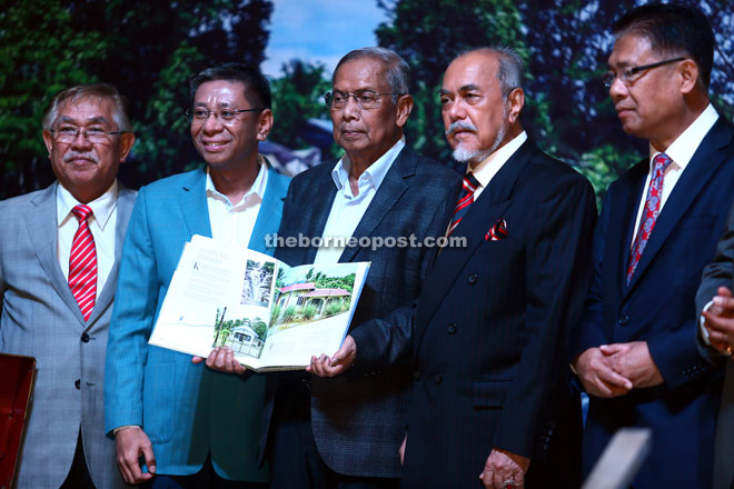 Adenan (centre) shows a page of the book to the press photographers at its launching. He is flanked by Azmi (left) and Asfia. — Photo by Muhammad Rais Sanusi