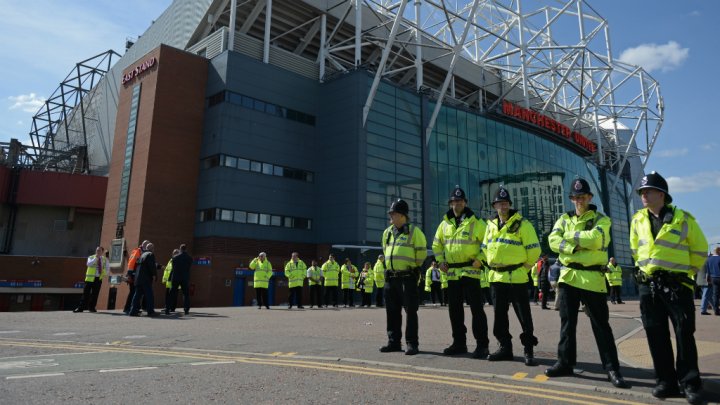 Police officers stand outside Old Trafford stadium in Manchester, England, on May 15, 2016, following a bomb scare. Photo by AFP