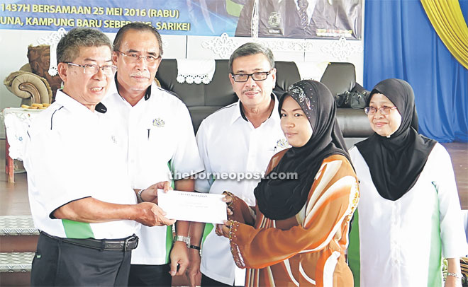 Materang (left) presents a contribution to a recipient as (from second left) Len, Anthony and Fatimah look on.