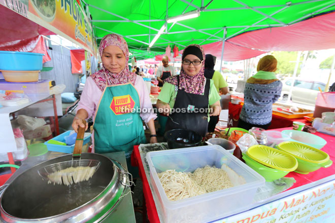 Salina (left) cooks kampua at the Ramadan bazaar. 