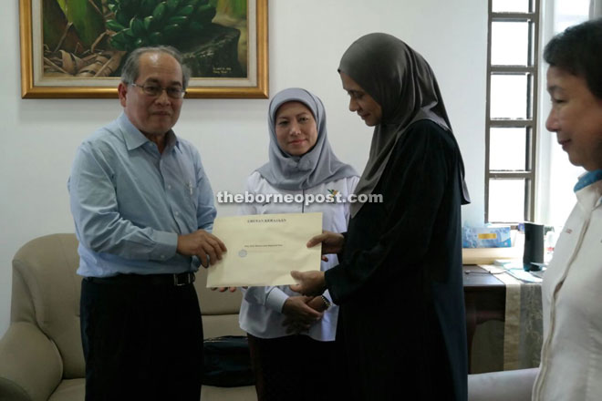 Uggah presenting the letter to Mastura while Nancy (second left) looks on.