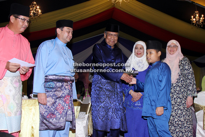 Adenan (third left) presents a gift to a child at the breaking of fast event with police personnel. Also seen are Mazlan (second left) and Jamilah (third right). — Photos by Chimon Upon 