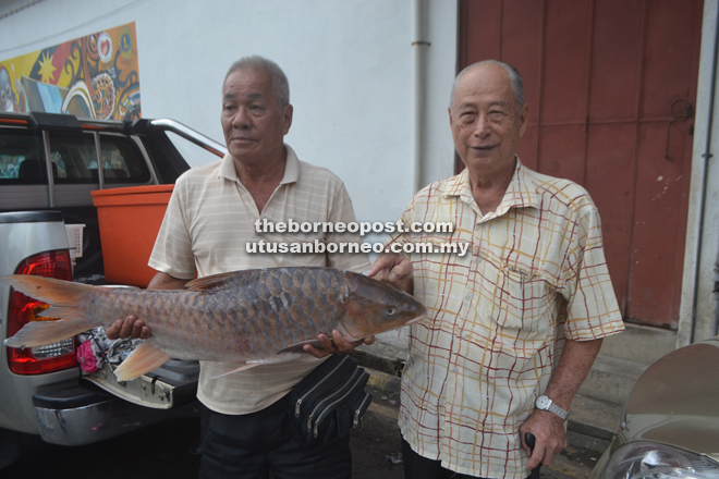 Ong (left) and a friend Law Ngo Hin proudly display the Empurau for the press at Belaga Wharf in Kapit.