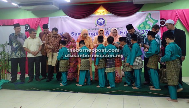  Jamilah (sixth left) presenting the monetary gifts to the orphans. At fourth left is Ahmad Lai.