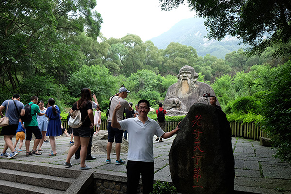 People posing with the stone statue of Laozi at the foot of Qingyuan Mountain.